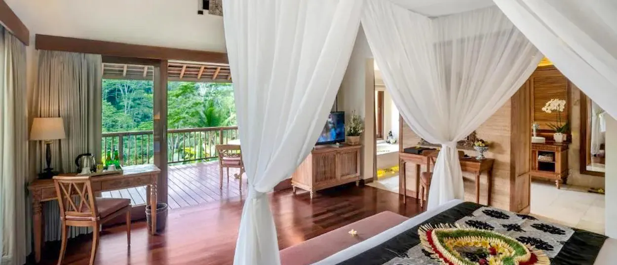 Luxurious bedroom at The Kayon Jungle Resort in Ubud, Bali, with a balcony overlooking lush greenery.