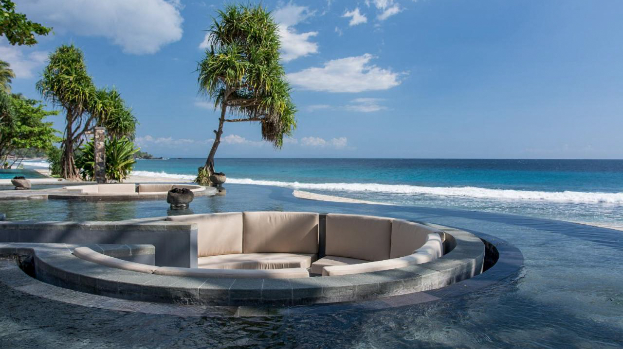 Luxurious infinity pool at Katamaran Resort Lombok with a sunken lounge area overlooking the blue ocean.