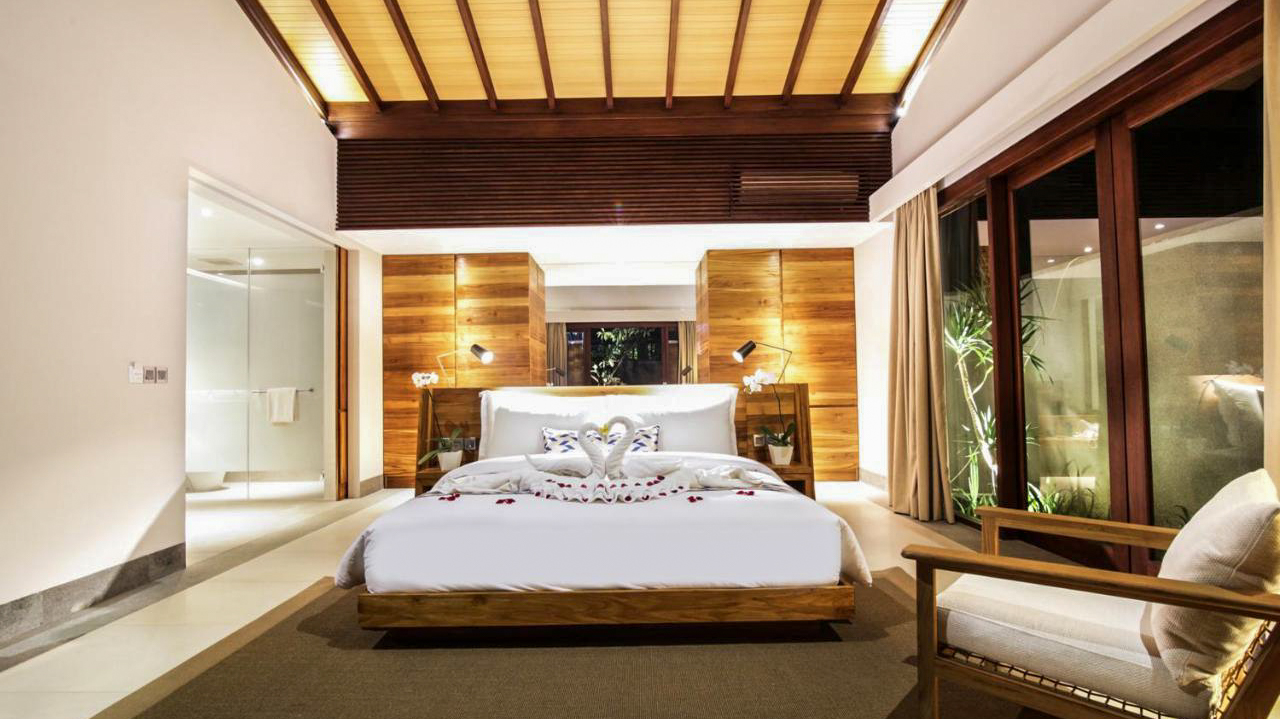 Romantic bedroom with a large bed, swan towels, and modern wooden decor at Katamaran Resort.
