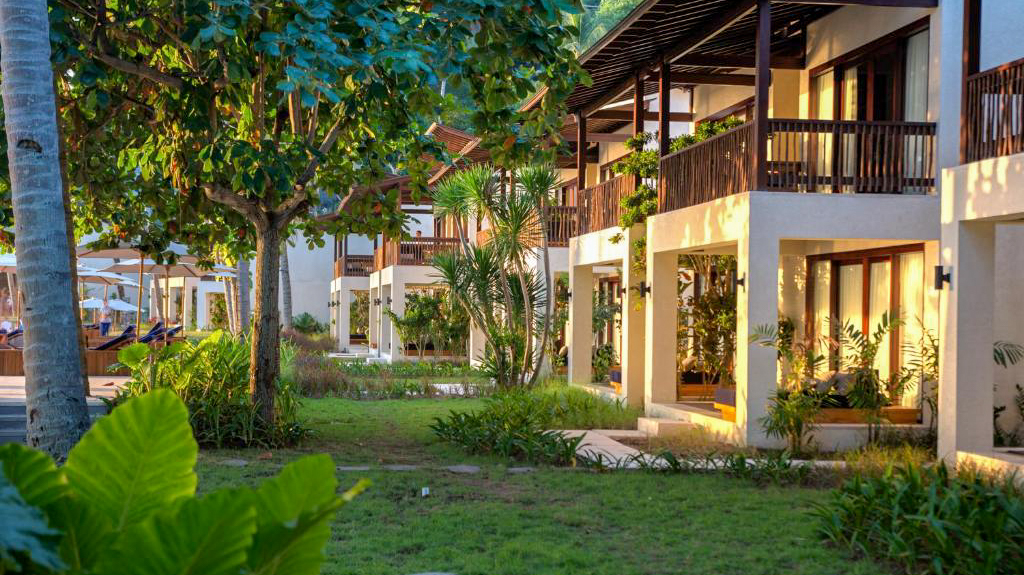 Lush green lawn and tropical trees frame modern resort buildings with balconies at Katamaran Resort, Lombok.