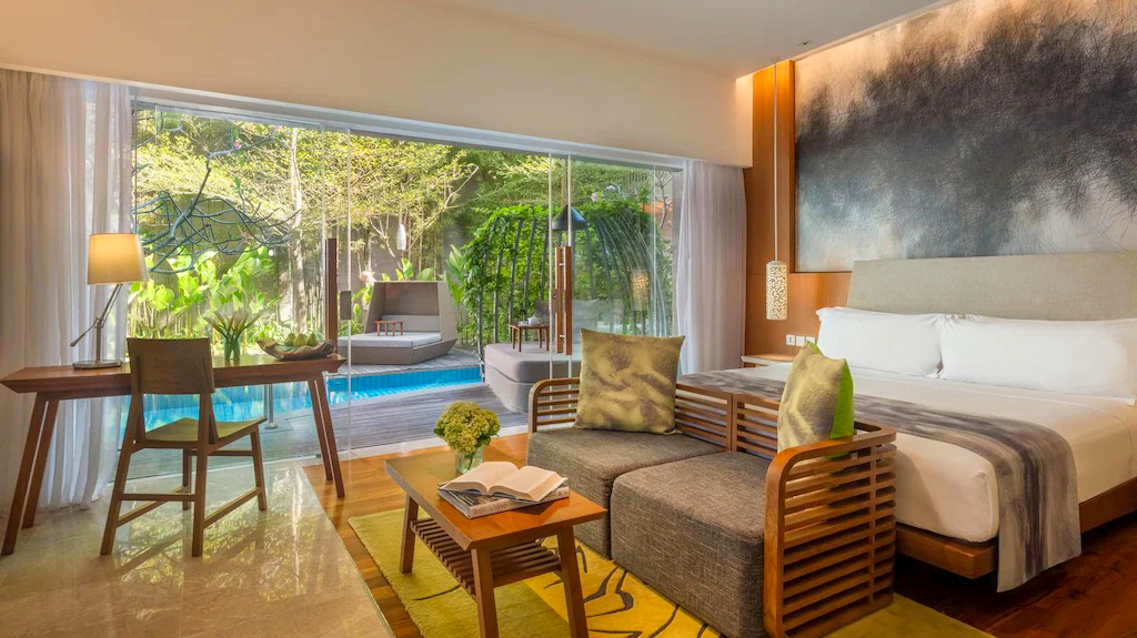 Luxury resort room in Sanur with a comfortable bed, sitting area, and private pool access.