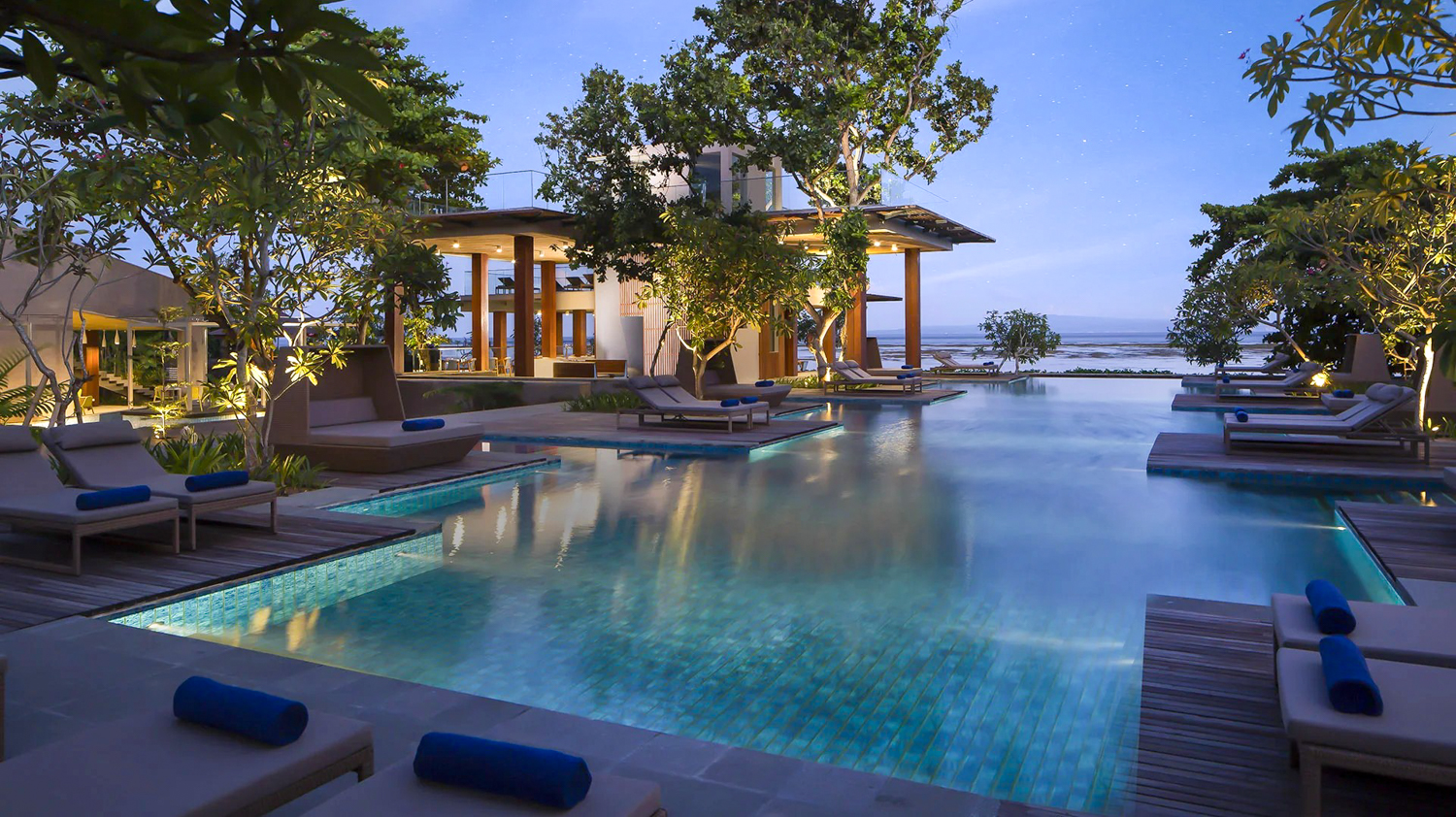 Luxurious infinity pool at Maya Sanur Resort, with comfortable lounge chairs and ocean views at twilight.