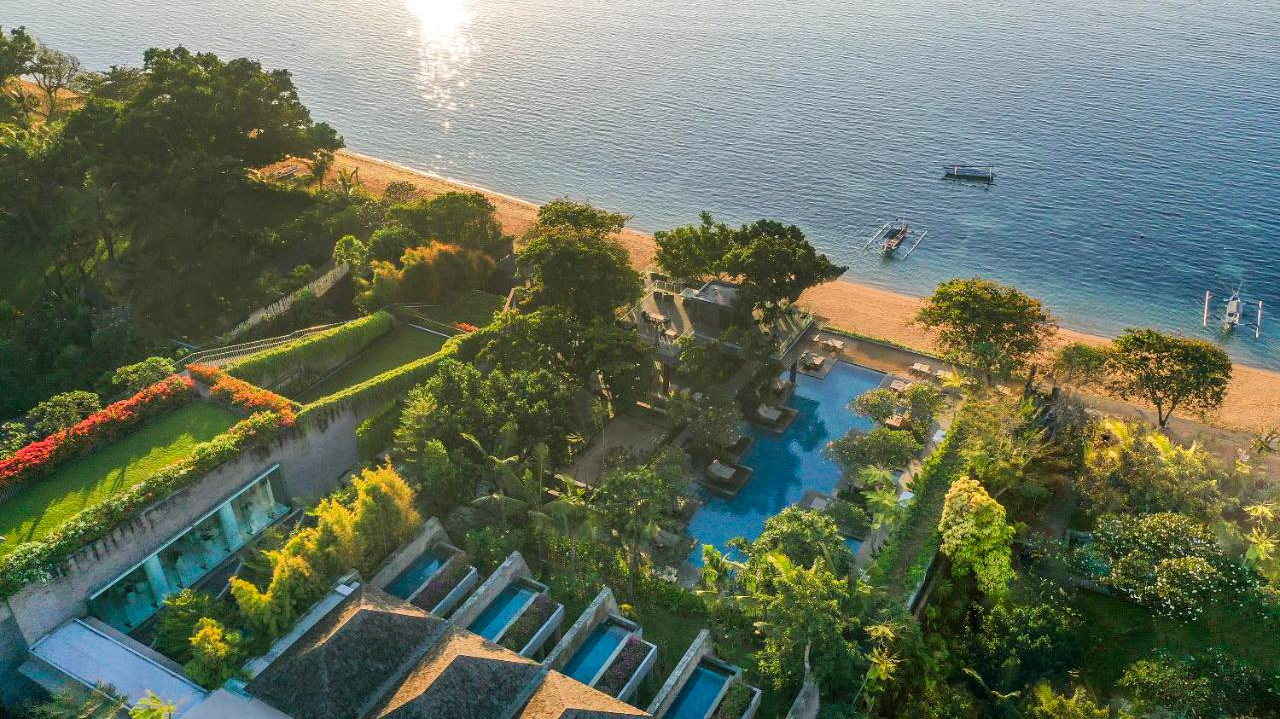 Aerial view of Maya Sanur Resort and Spa, featuring beachfront pools, lush gardens, and a serene ocean.