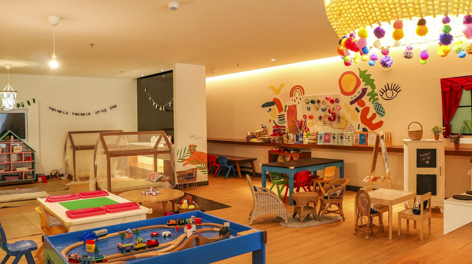 Bright and colorful children's play area with train set, dollhouse, and craft station at Maya Sanur Resort.