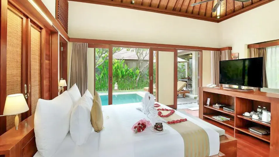 Elegant Bali villa bedroom with a king bed, romantic decor, and private swimming pool access.