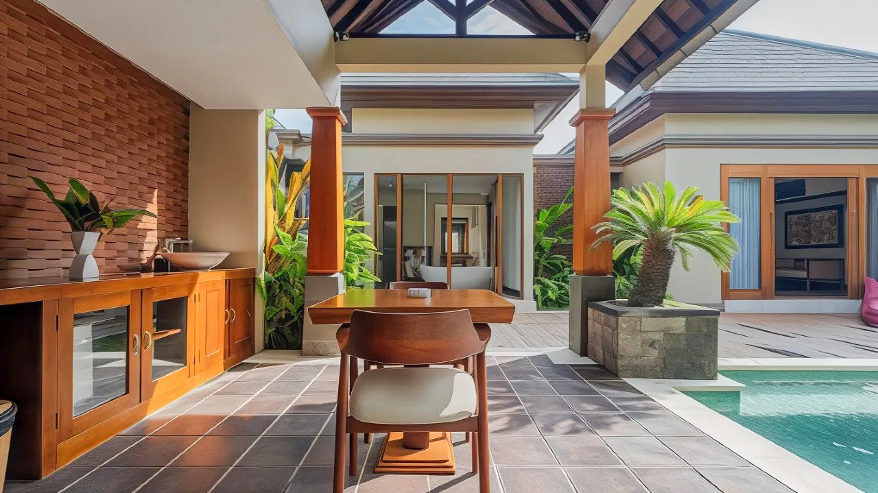 Luxurious outdoor patio with a dining table, sink, and swimming pool at a Bali resort.