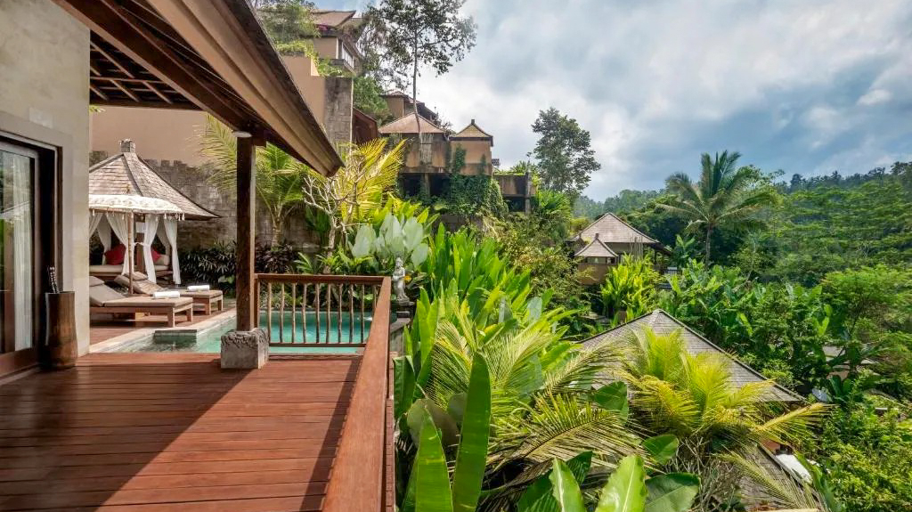 Luxurious Bali jungle resort balcony with a private plunge pool and daybed among lush trees.