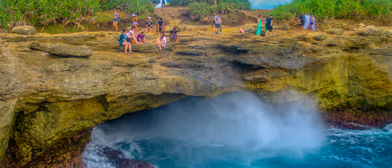 Tourists watch powerful waves crash against the rocky cliffs at Devil's Tear, Nusa Lembongan.
