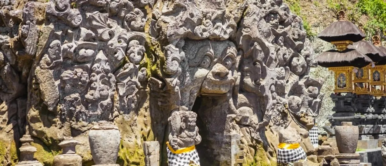 Intricate stone carvings of a mythical face at the entrance of Goa Gajah temple in Bali.