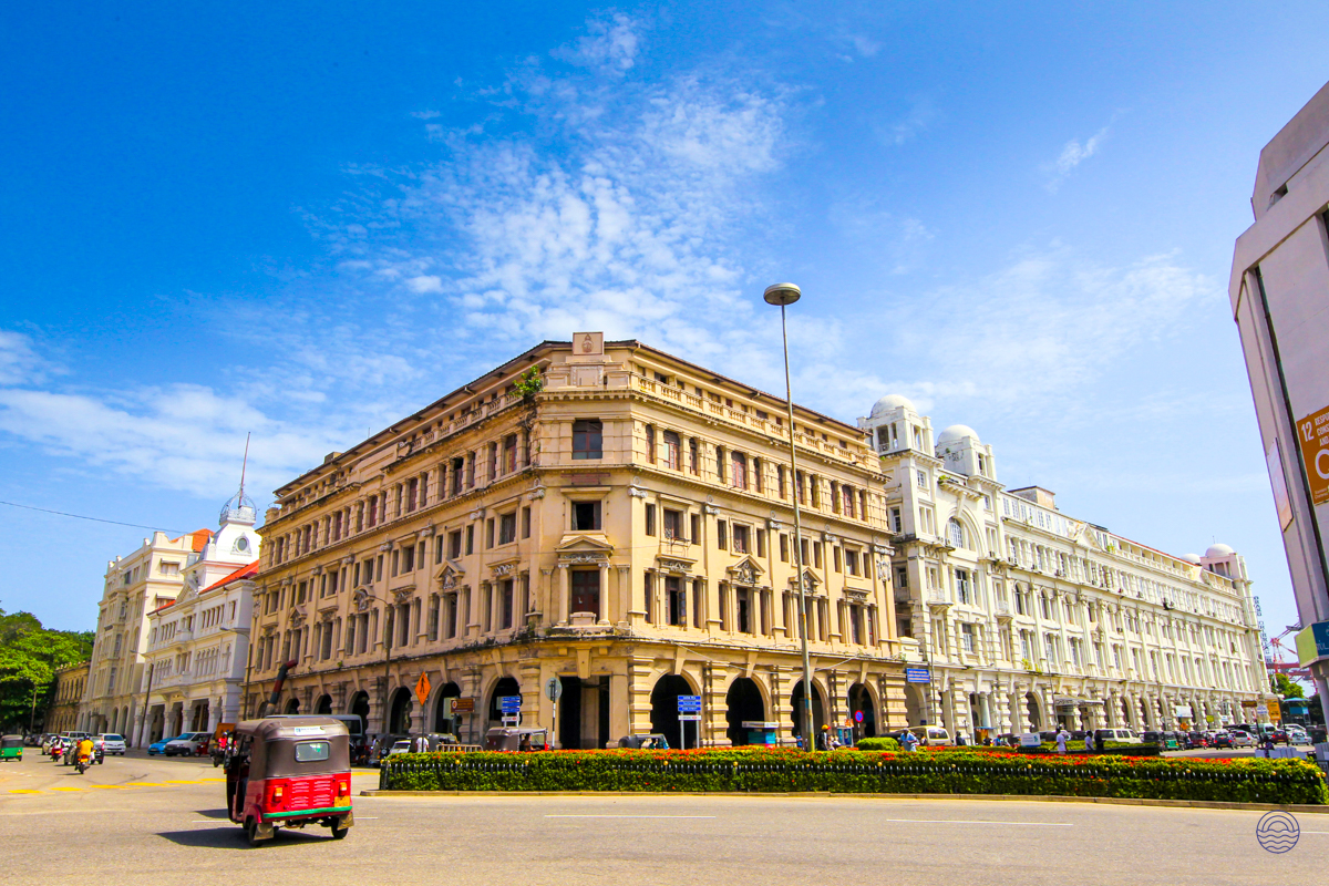 A vibrant street in Colombo featuring grand colonial architecture under a bright blue sky.