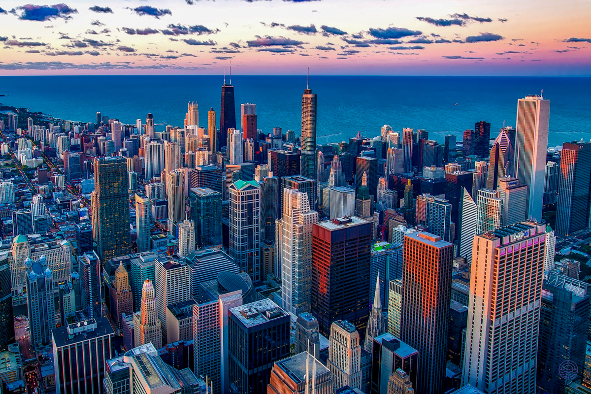 Stunning aerial view of a bustling metropolis with countless skyscrapers against a colorful sunset sky.