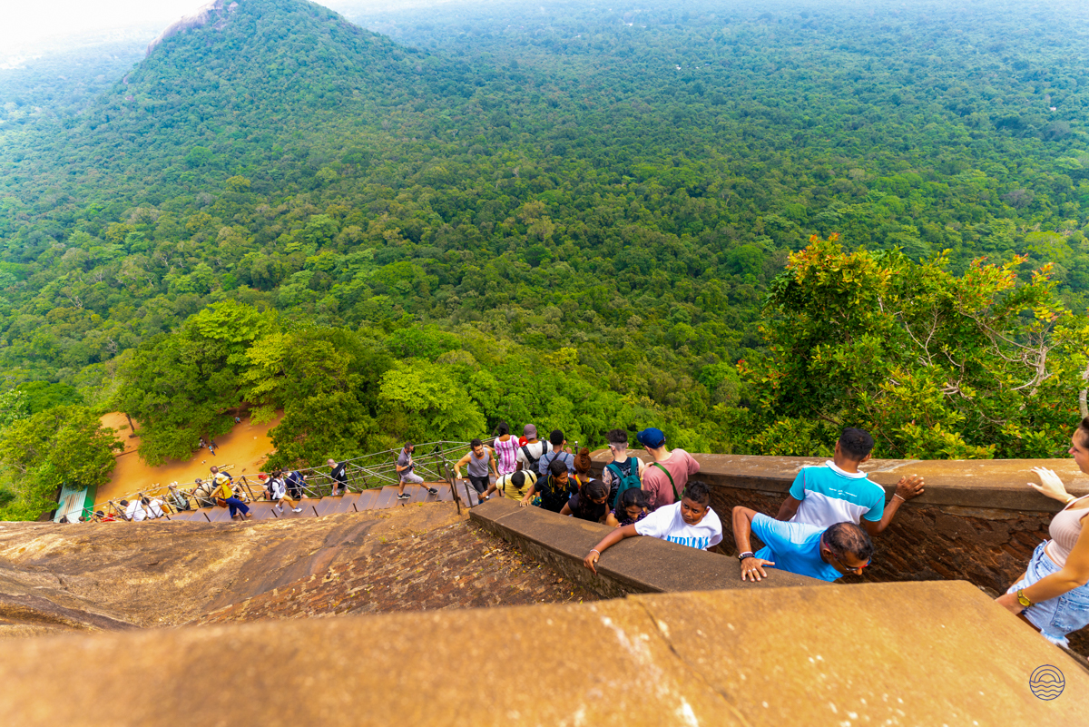 Adventurous travelers ascend the historic Sigiriya Lion Rock, surrounded by breathtaking green landscapes.