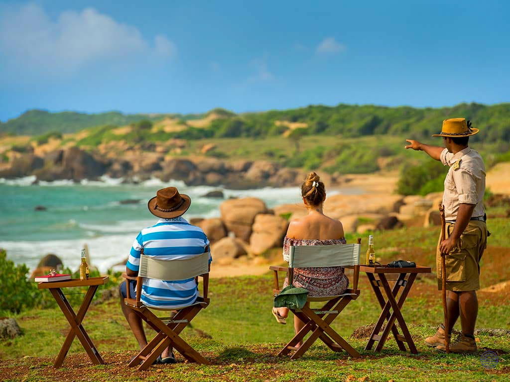 A couple and their guide enjoying scenic ocean views from a clifftop in Yala National Park.
