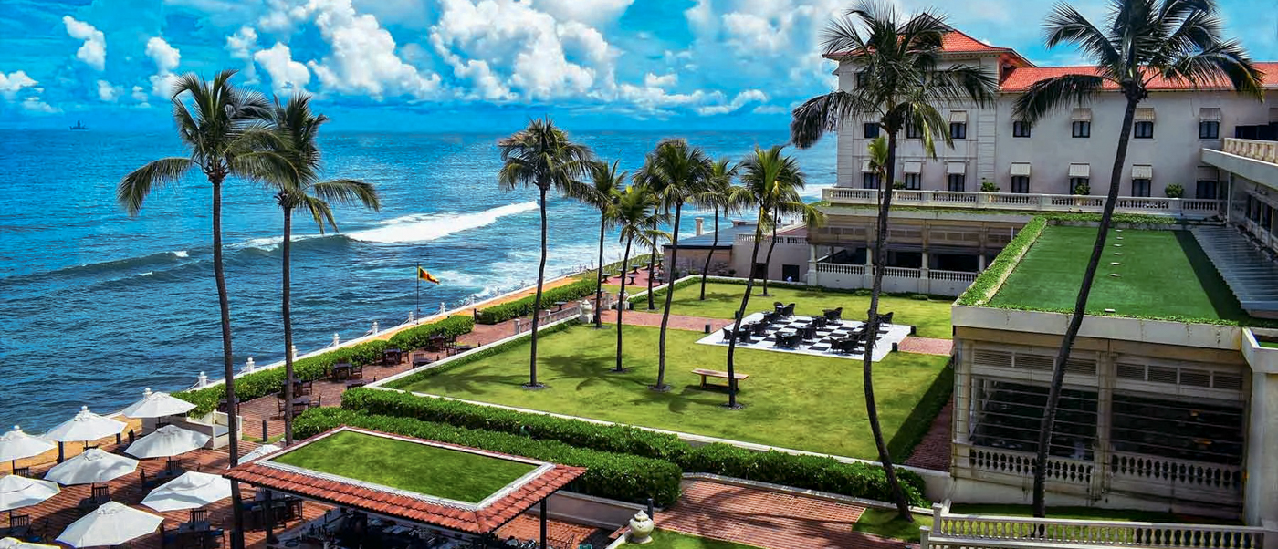 Elegant hotel with palm trees and green lawns overlooking the blue ocean in Colombo, Sri Lanka.
