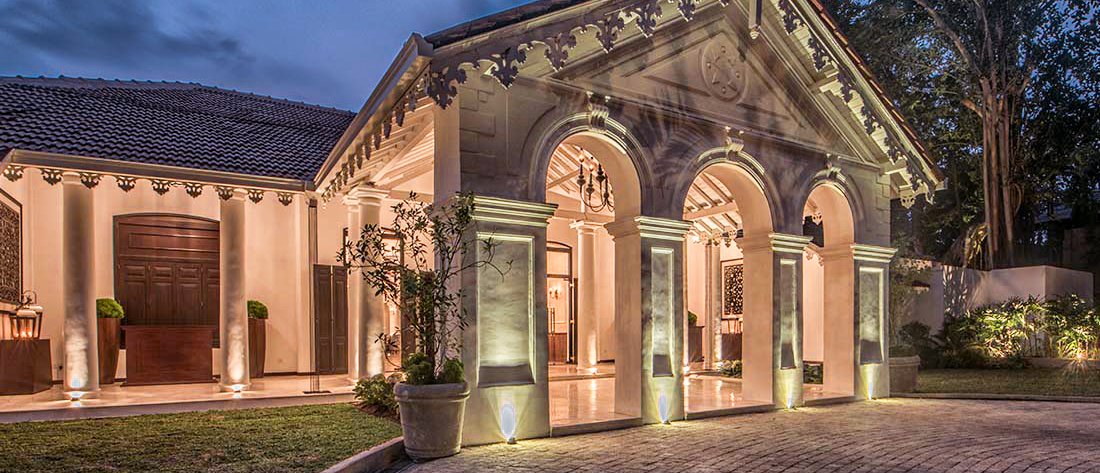 The grand, elegantly lit entrance of a colonial-style residence at dusk in Colombo.