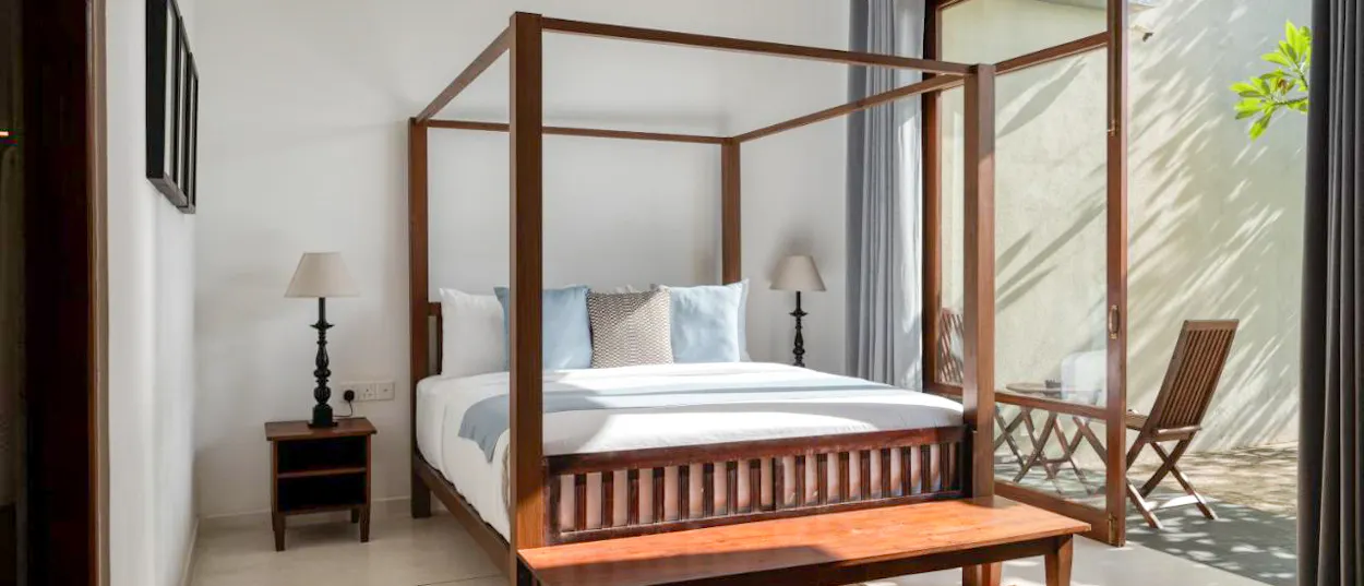 A serene bedroom with a wooden four-poster bed and bright patio access in Weligama.