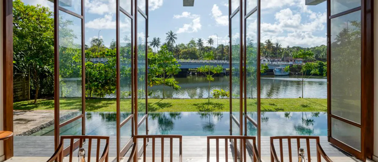 Serene view from a luxurious villa in Weligama, with an infinity pool overlooking a tropical river.