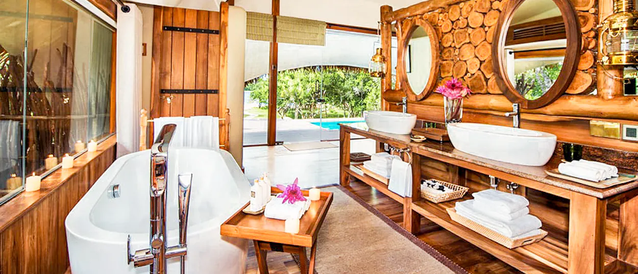 Luxurious bathroom with wooden decor, freestanding tub, double sinks, and private plunge pool view in Yala.