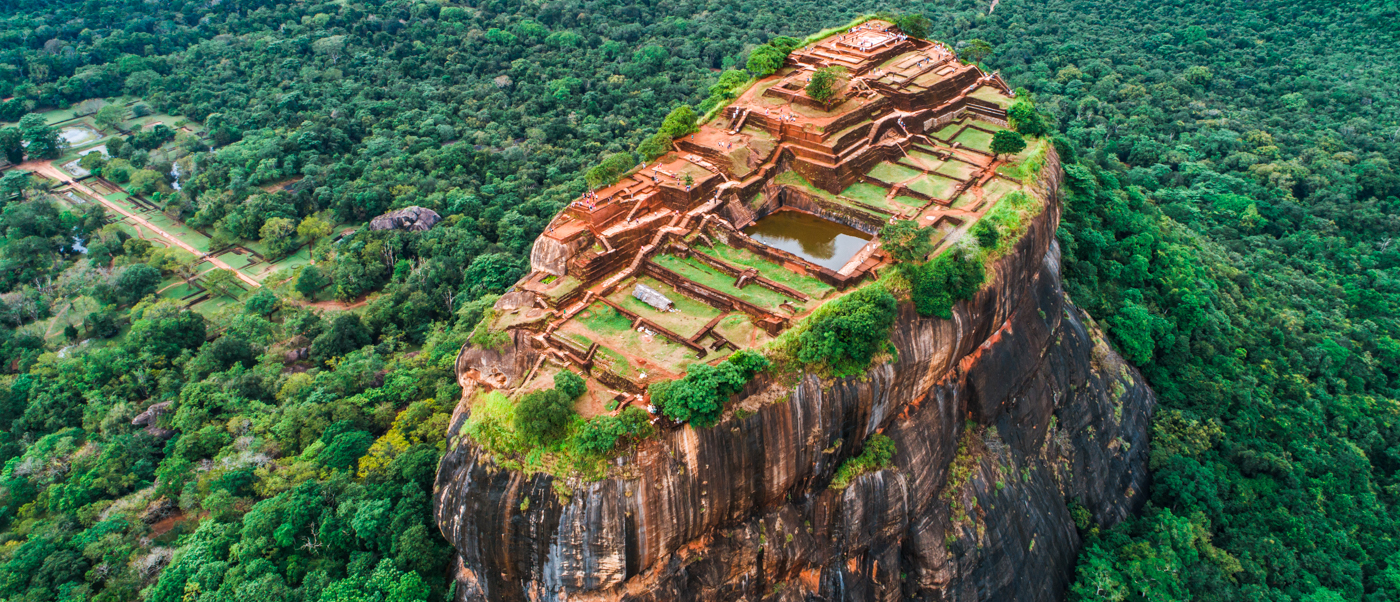 Ancient Sigiriya Lion Rock fortress ruins on a towering rock, surrounded by lush Sri Lankan jungle.