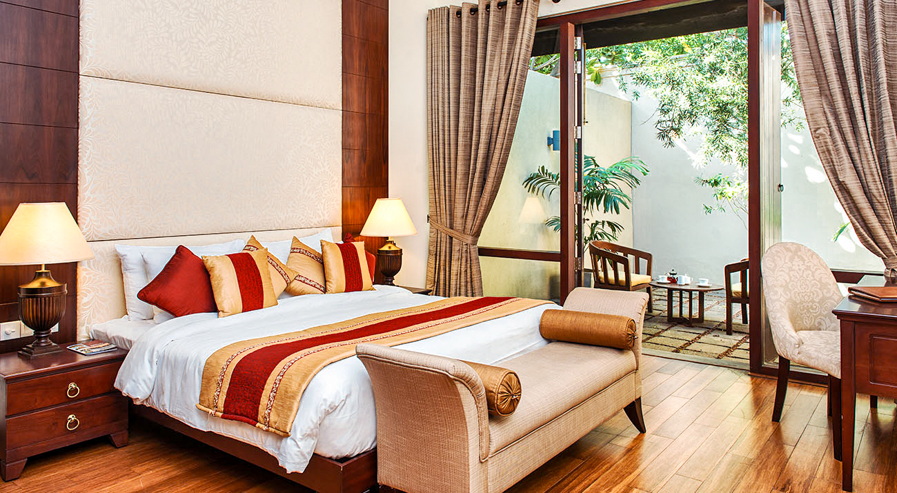 Luxurious hotel room in Colombo with a large bed, elegant decor, and a private patio.