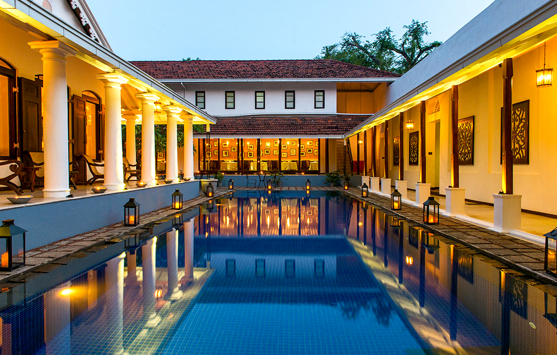 Serene hotel swimming pool in Colombo, Sri Lanka, with warm lighting and glowing lanterns at twilight.