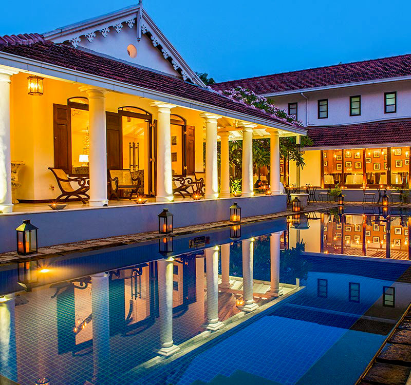 Luxurious colonial hotel in Colombo with a tranquil pool reflecting its elegant architecture at twilight.
