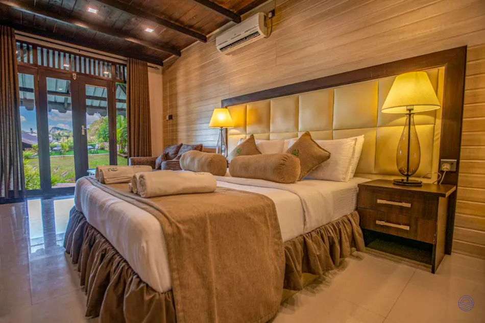 Inviting hotel suite in Ella featuring a comfortable bed and doors opening to a beautiful green garden.