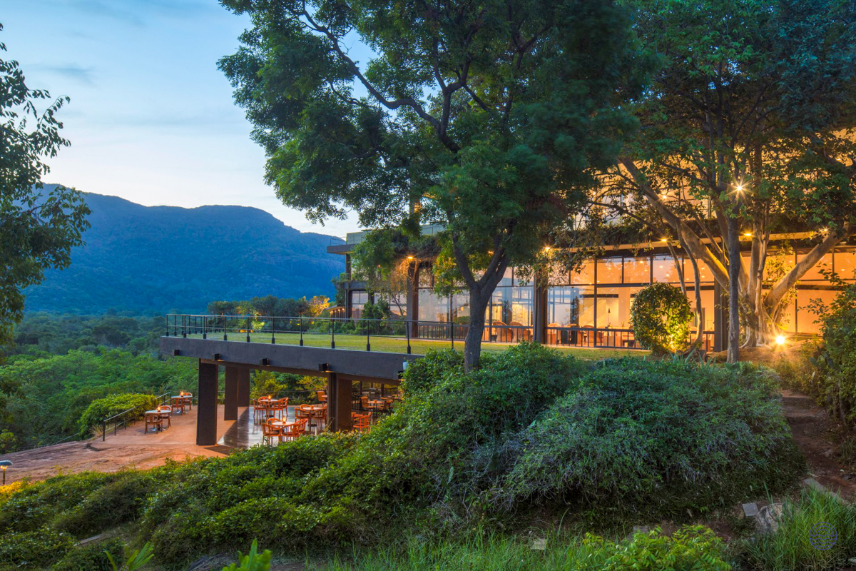 Heritance Kandalama resort at dusk, with illuminated terraces and dining areas blending seamlessly into lush greenery.