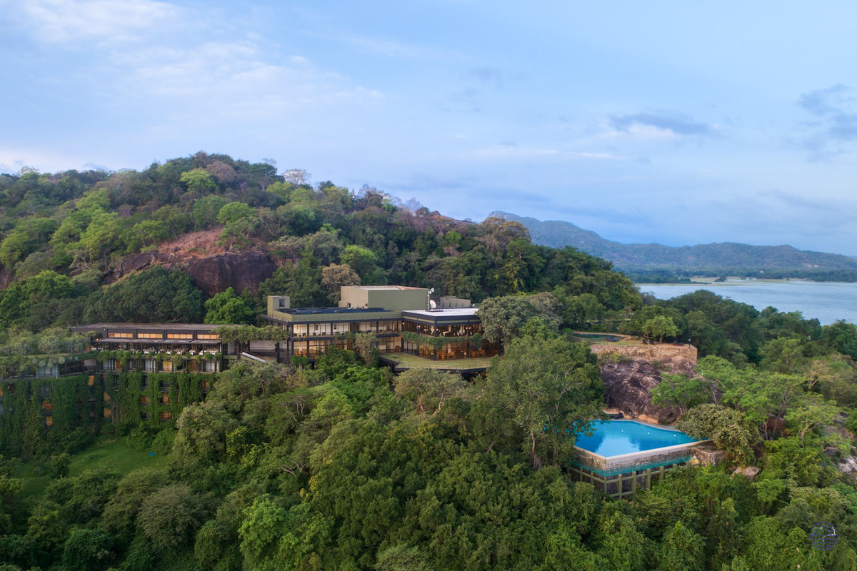 Heritance Kandalama hotel blends into the green hillside with a serene pool and distant lake.