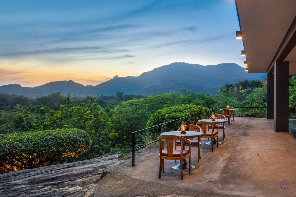 Romantic outdoor patio with candlelit tables at dusk, offering panoramic views of Sri Lankan mountains.