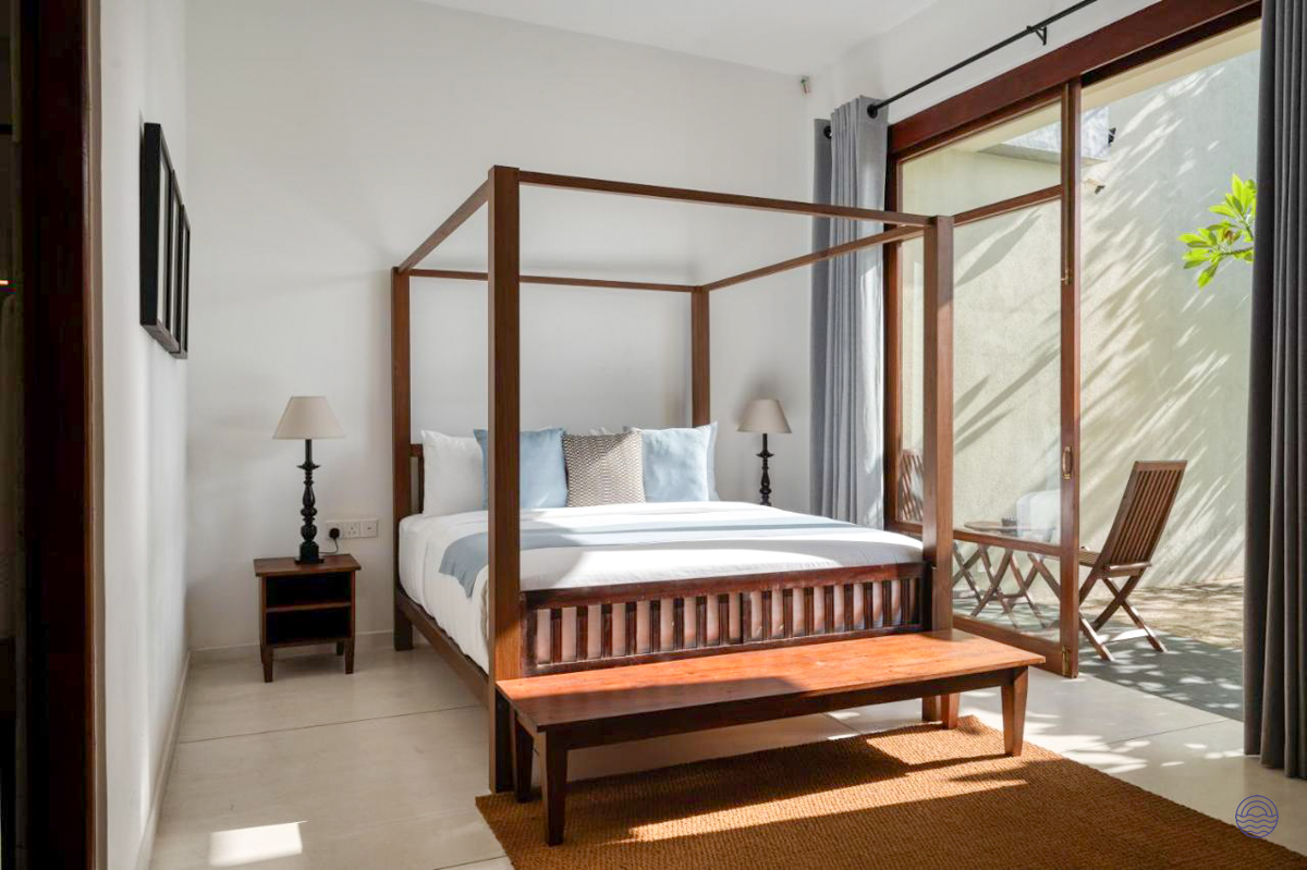 Bright deluxe double room with a wooden four-poster bed and private patio in Weligama.