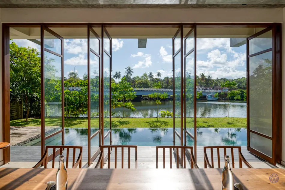 Open doors reveal a beautiful view of a calm river, lush trees, and a distant bridge.