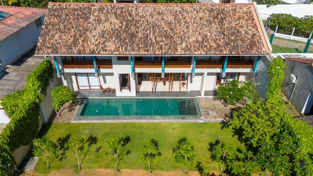 Modern two-story villa in Weligama featuring a long swimming pool and lush green lawn.