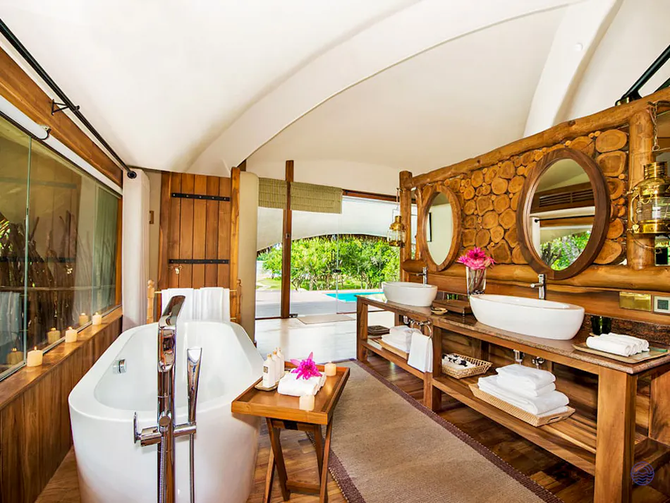Spacious, luxurious bathroom with a freestanding tub, wooden vanity, and outdoor plunge pool view.