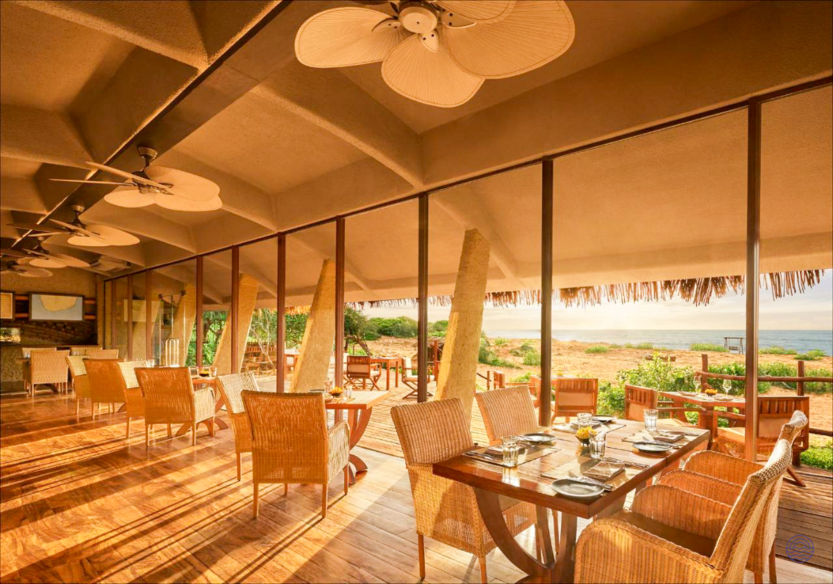 Elegant restaurant interior with large windows offering stunning views of the sandy coast in Yala.