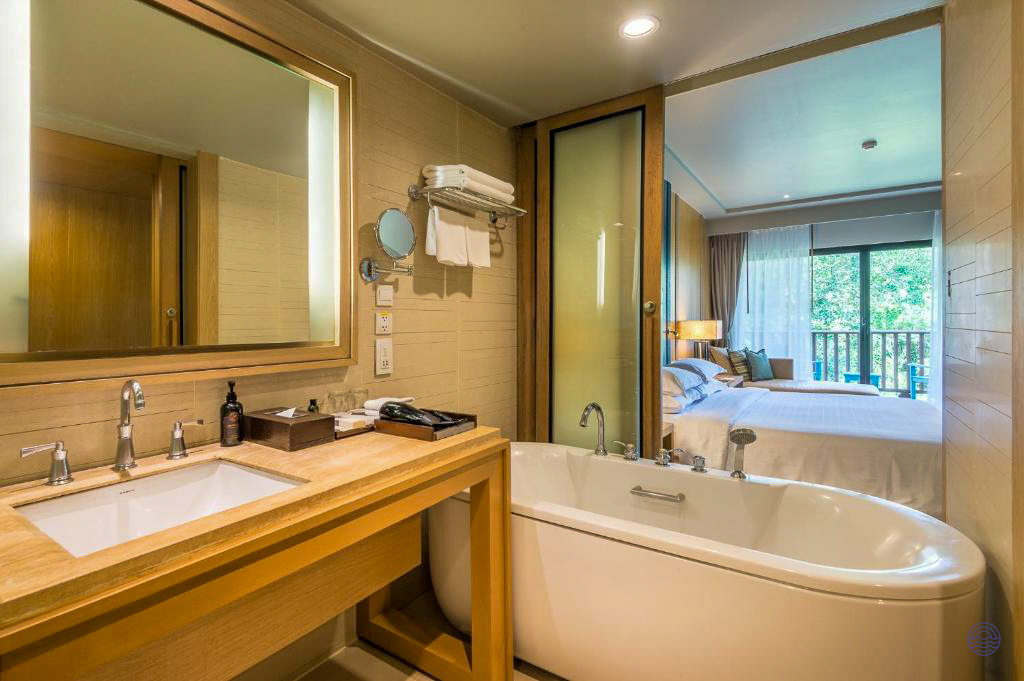 Elegant hotel bathroom with a large tub and a view into the comfortable bedroom in Krabi.