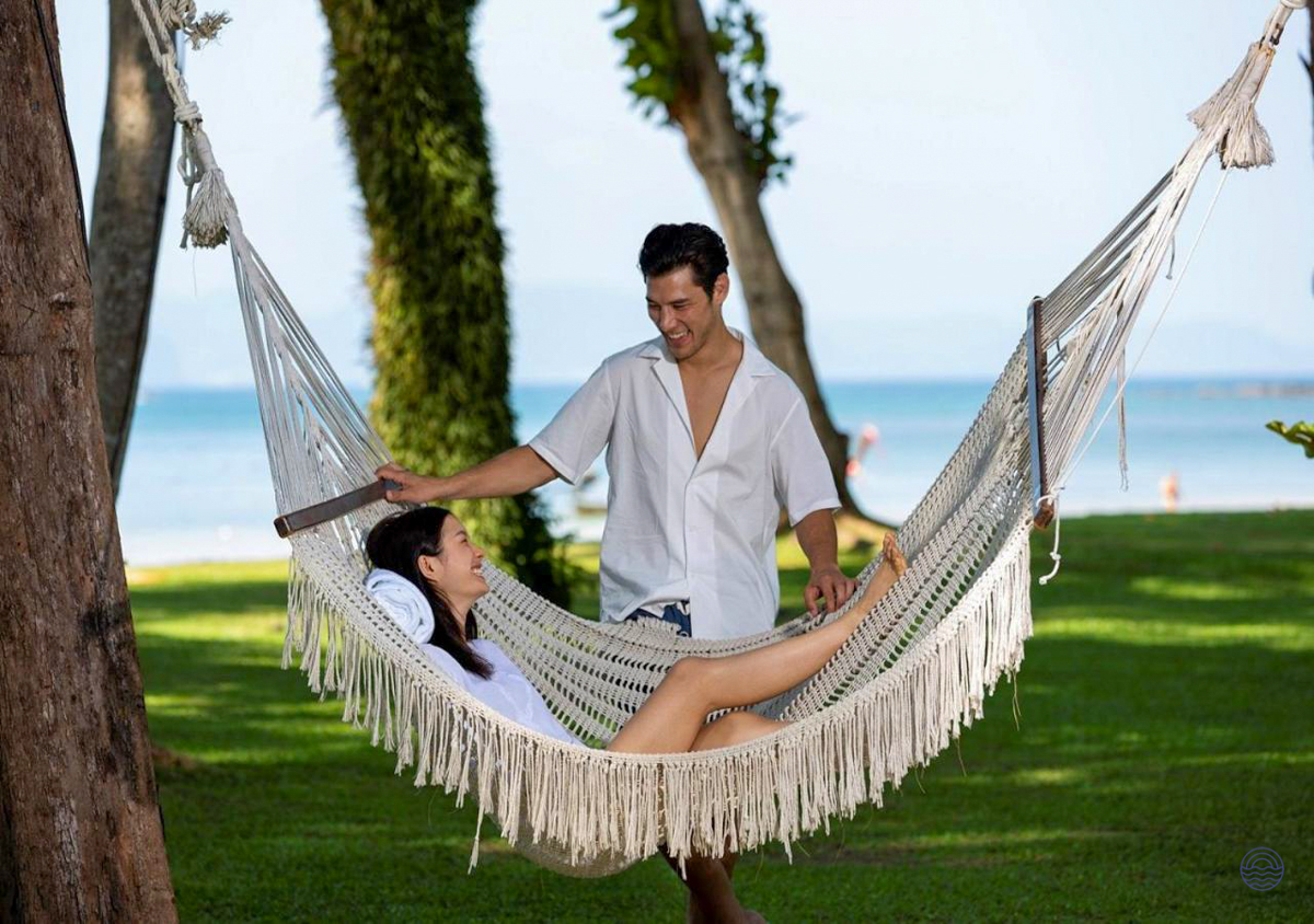 A couple enjoys a romantic moment in a hammock by the beach in Krabi, Thailand.