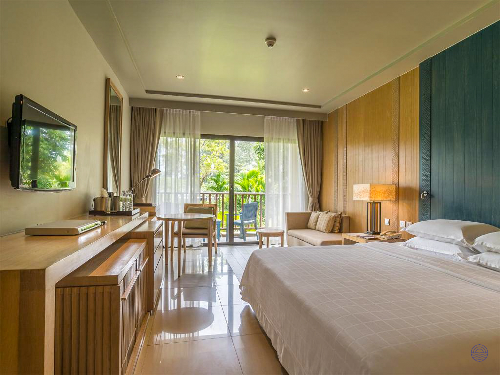 Luxurious hotel room in Krabi with a comfortable bed and private balcony overlooking tropical gardens.