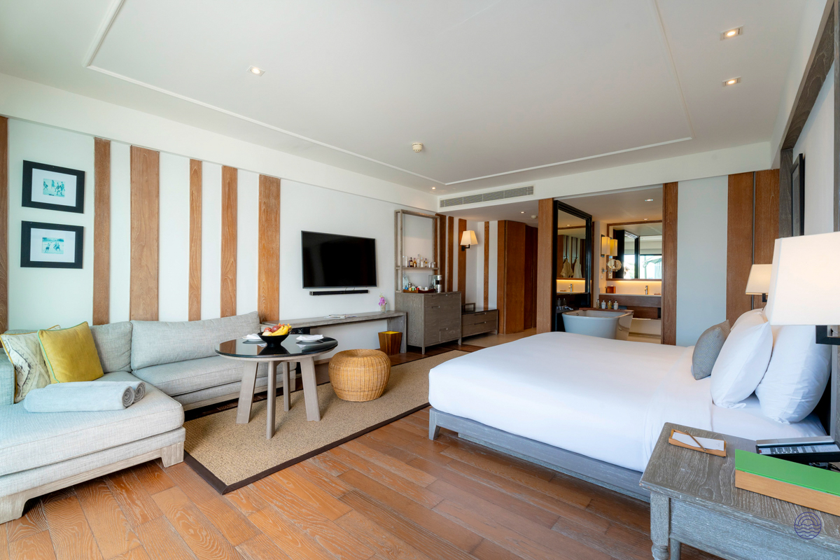 A serene and luxurious hotel room in Chiang Mai, featuring a large bed, sofa, and elegant bathroom.