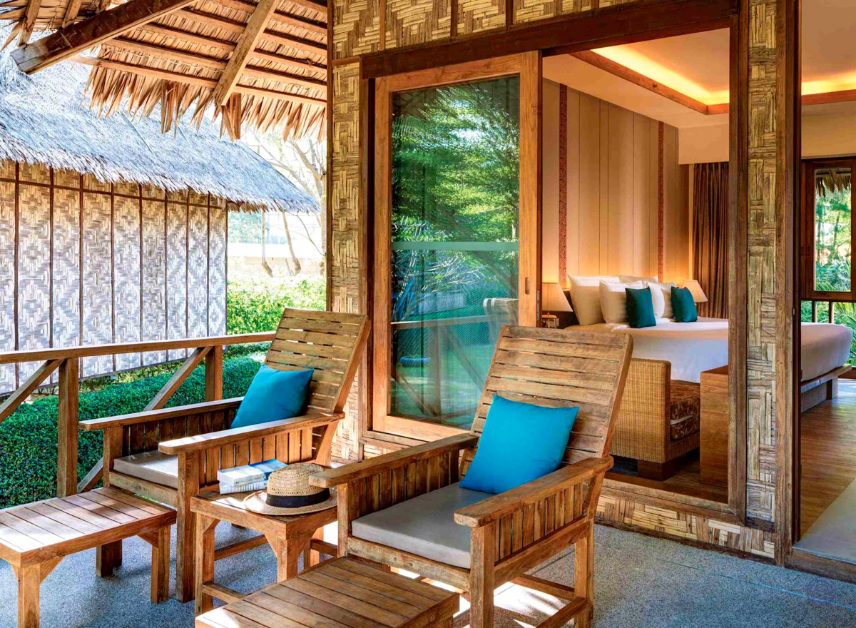 Tropical resort room with a private balcony, wooden chairs, and a comfortable bed in Koh Phi Phi.