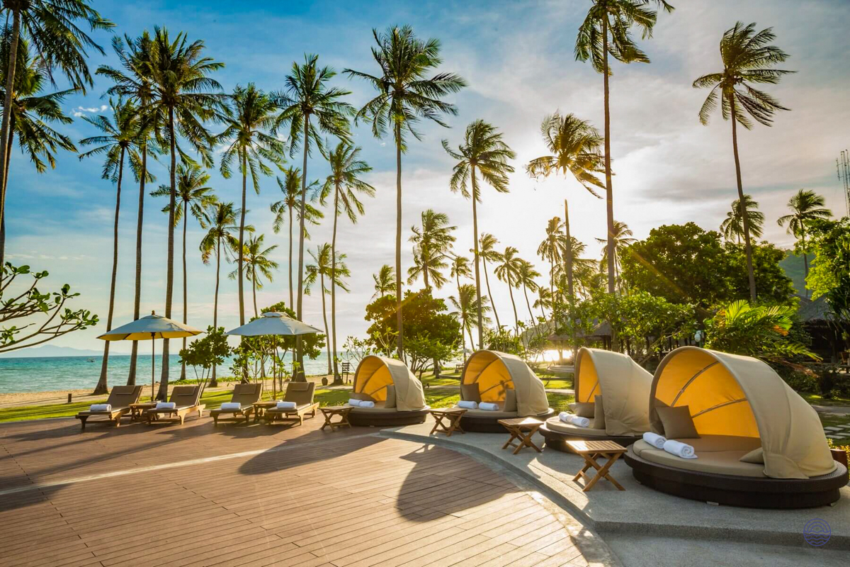 Golden hour light illuminates luxurious daybeds and sun loungers on a tropical beach in Koh Phi Phi.