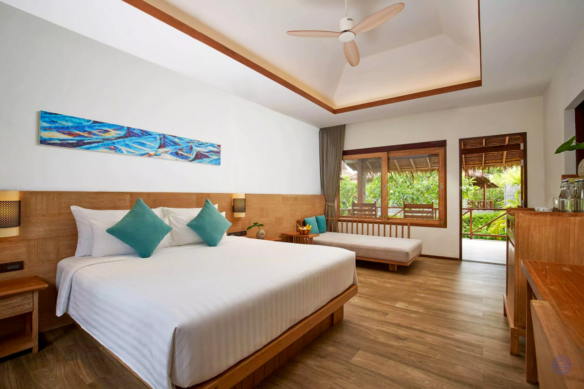 Inviting resort room in Koh Phi Phi with a large bed, daybed, and lush tropical garden outside.