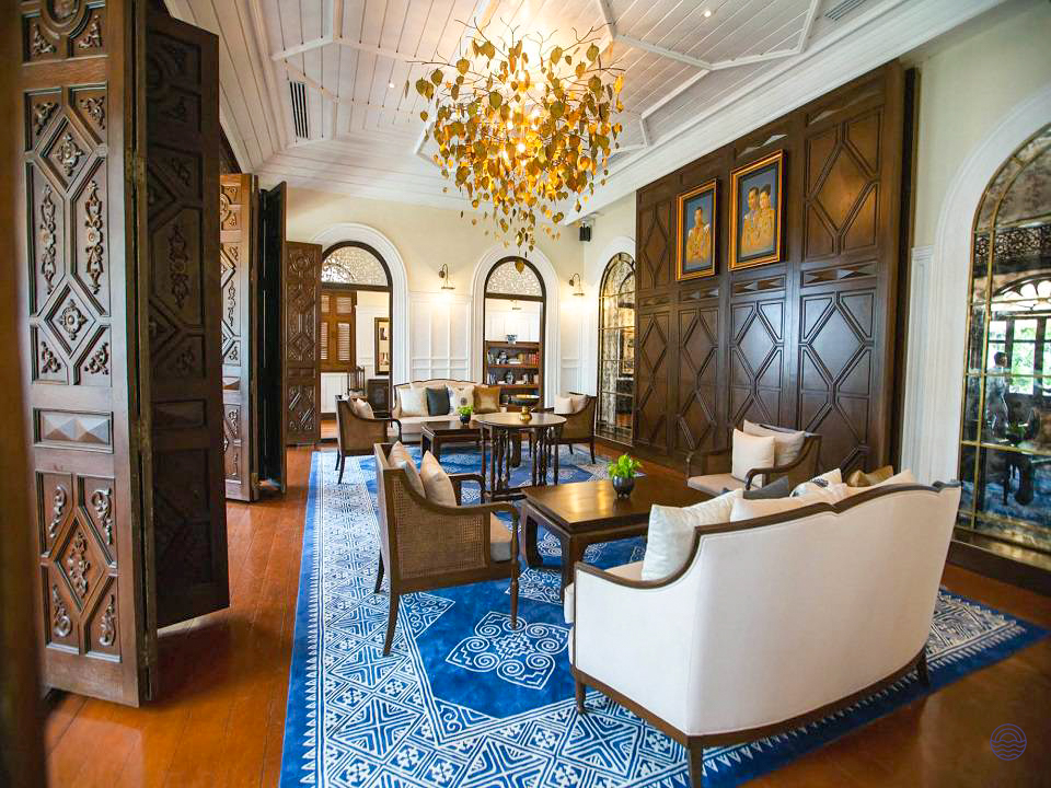 Spacious and elegant hotel lounge in Bangkok with comfortable sofas, a grand chandelier, and patterned rug.