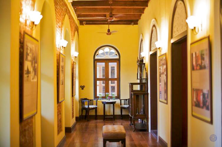 A charming hotel hallway in Bangkok with yellow walls, wooden floors, and a cozy seating area.