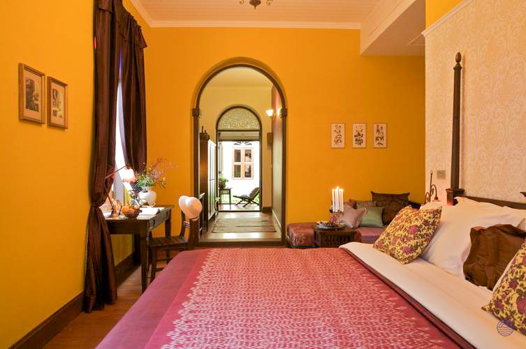 Elegant and spacious hotel room in Bangkok with vibrant yellow walls and a large, inviting bed.