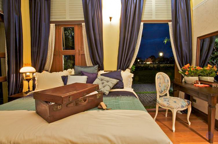 A charming hotel room with a comfortable bed and open suitcase, welcoming guests to Bangkok.
