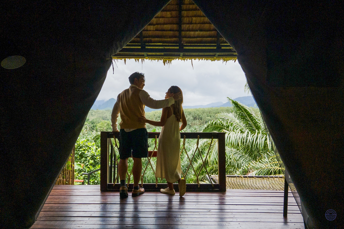 A couple embraces on a balcony, admiring the lush rainforests of Khao Sok National Park.