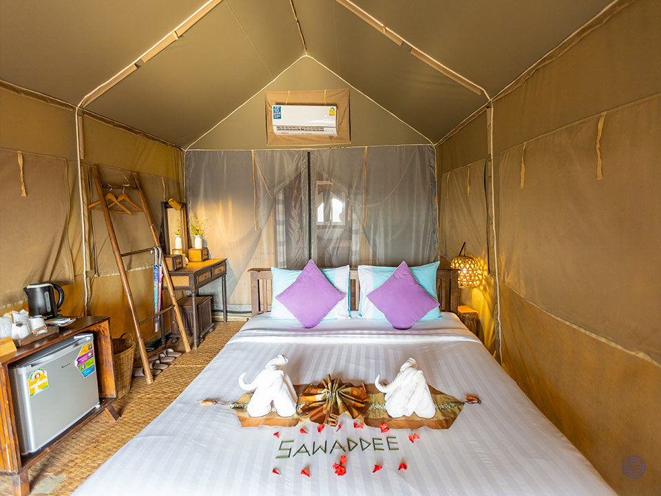 Comfortable glamping tent in Khao Sok, Thailand, with a bed adorned with 'Sawaddee' in flower petals.