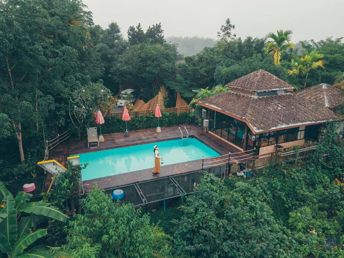 A person relaxes by a tranquil swimming pool at a boutique camp in the lush Khao Sok rainforest.