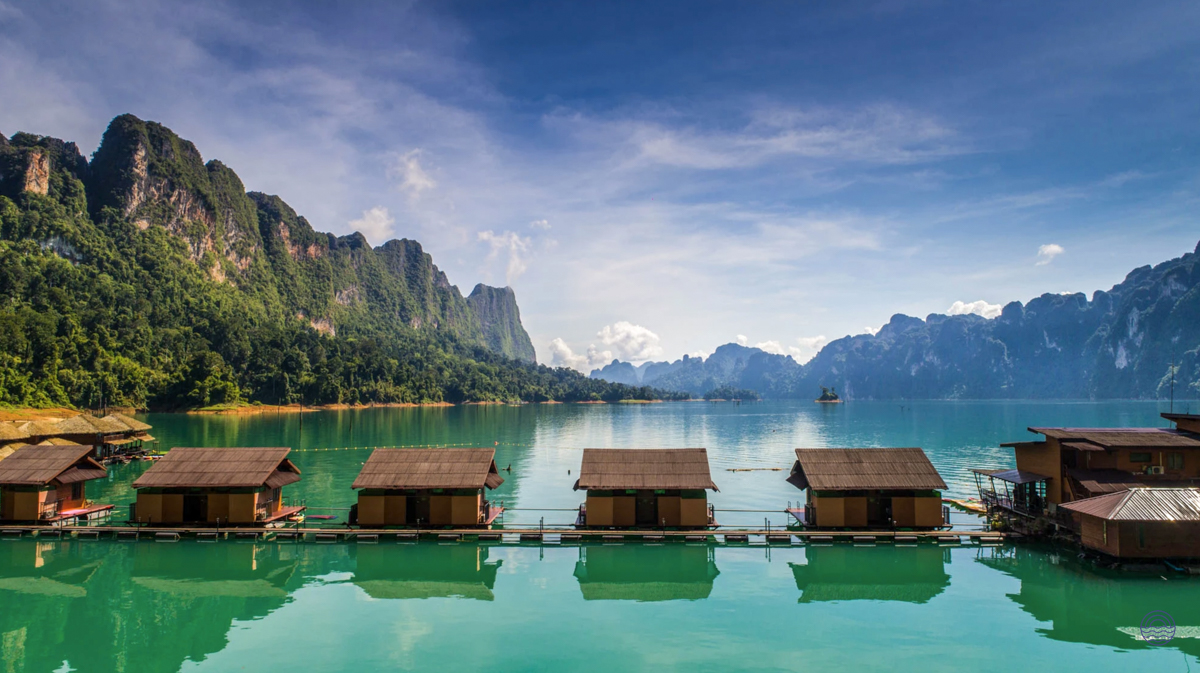 Serene floating bungalows on the turquoise Chiewlan Lake in Khao Sok, framed by majestic green mountains.
